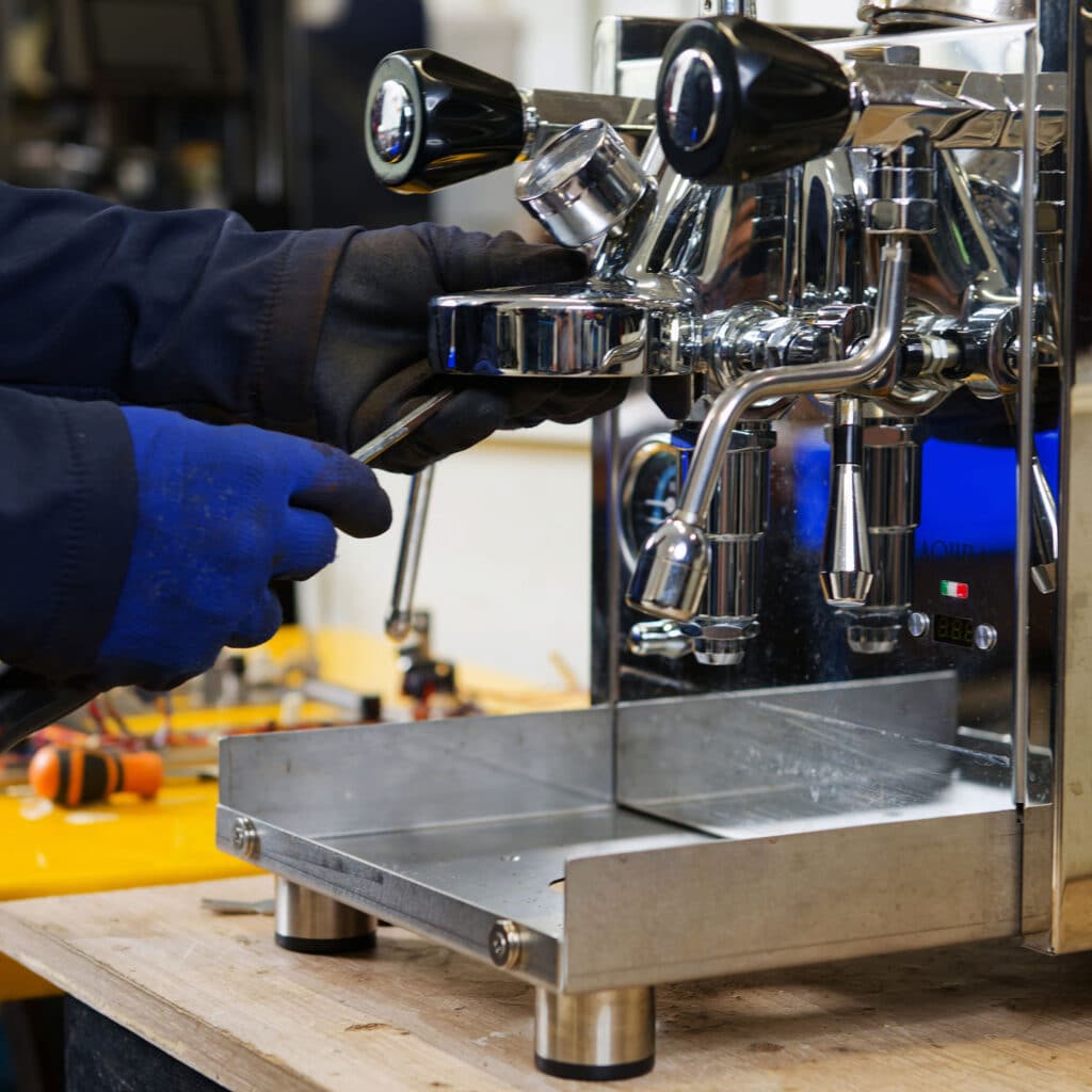 Technicien Mathieu Paris ajustant le groupe de percolation d'une machine à café professionnelle chromée