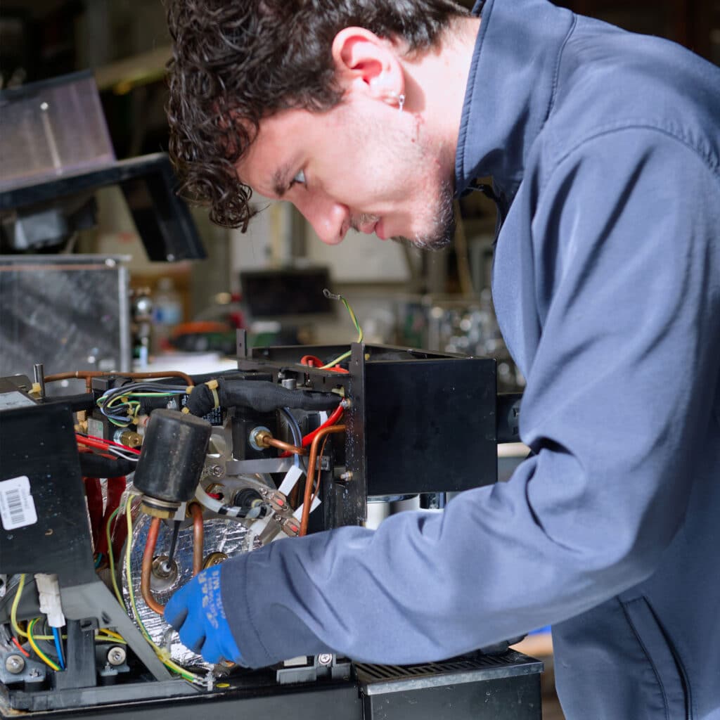 Technicien Mathieu Paris réparant le circuit électrique d'une machine à café professionnelle